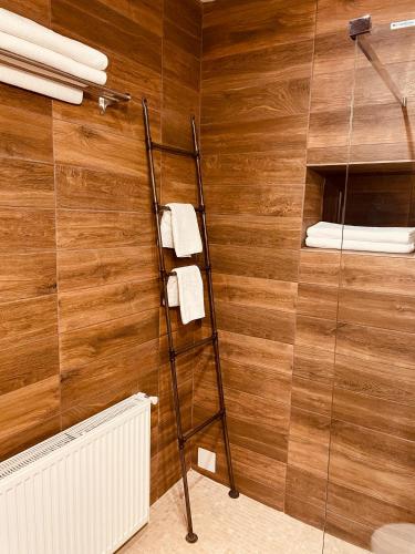 a bathroom with a shower with a wooden wall at Casa Pisica Noastra in Breaza