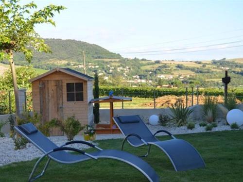 un patio con dos bancos azules en el césped en Coeur de Vignes, en Saint-Péray