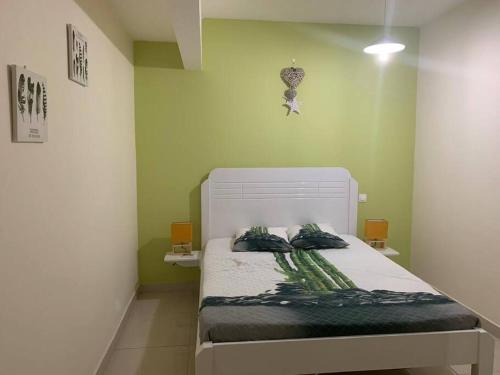 una camera da letto con un letto bianco e pareti verdi di Superbe appartement pour 6 personnes à Trinité a La Trinité