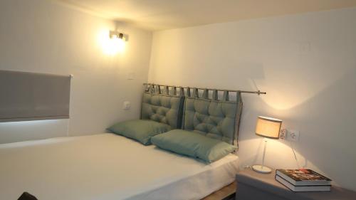 um quarto com uma cama com almofadas verdes e um candeeiro em Cozy apartment near the city centre em Iráclio