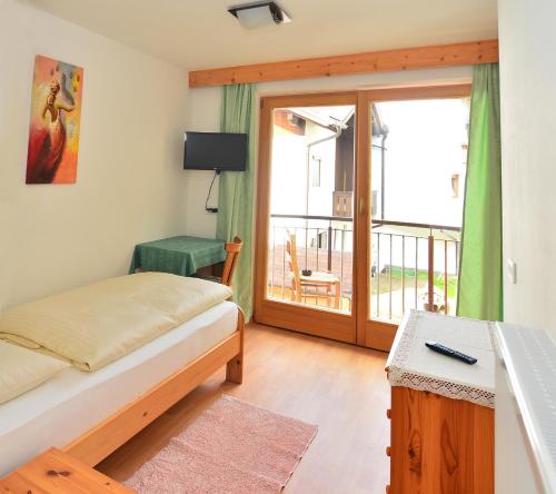 1 dormitorio con 1 cama y puerta a un balcón en Garni Margherita, en Corvara in Badia