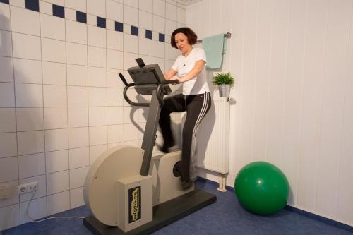 a woman riding on an exercise machine in a room at Landhotel Schöll in Parsberg