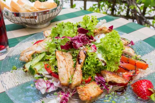 a plate of food with a salad and a strawberry at Landhotel Schöll in Parsberg
