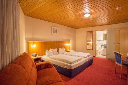 um quarto de hotel com uma cama e um sofá em Landhotel Schöll em Parsberg