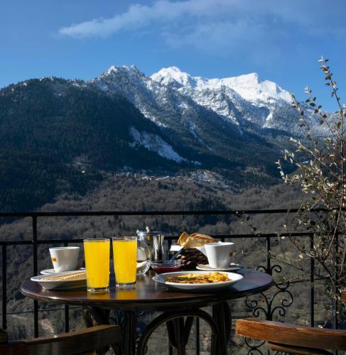 a table with food and drinks on a balcony with a mountain at Δωμάτια με θέα in Méga Khoríon