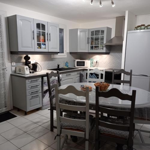 une cuisine avec des armoires blanches et une table et des chaises dans l'établissement Villa Cara, 6 personnes, proche plage et commerces, secteur calme, Classé 3 étoiles, au Barcarès