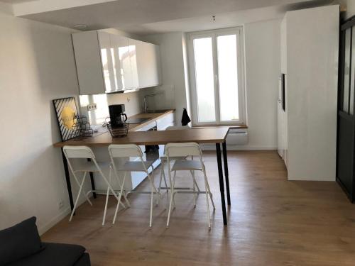 une cuisine avec une table et des chaises dans une pièce dans l'établissement Le Spot, appartement spacieux à 30m de la mer 45m2, à Luc-sur-Mer