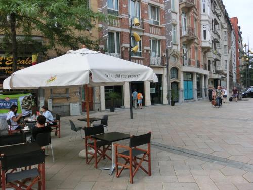 a table and chairs with an umbrella on a city street at Hotel Aviation in Brussels