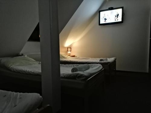 Habitación con 2 camas y TV en la pared. en RESTAURACJA & PENSJONAT SZAMANKO, en Hrubieszów