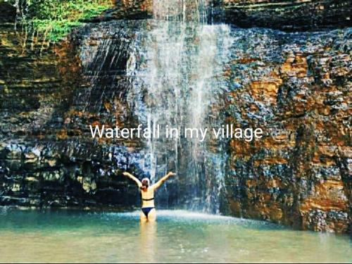 une femme debout dans l'eau sous une cascade dans l'établissement Iveri House, à Koutaïssi