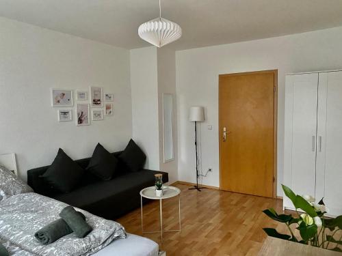 a living room with a black couch and a table at Modern & cozy Rooms Leipzig-Gohlis in Leipzig