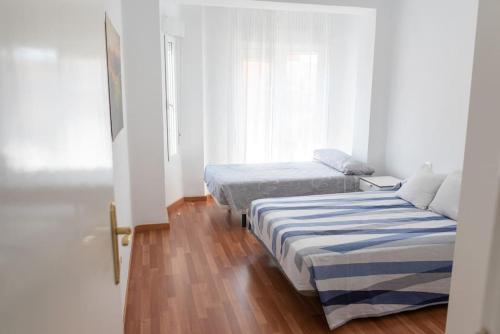 sypialnia z dwoma łóżkami i oknem w obiekcie Apartamento Alexa, a 800mts Catedral WiFi Smart TV w Murcji