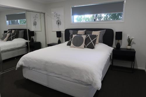 a bedroom with a large white bed and two windows at Sunshine Coast Beach House - 2 mins to beach in Parrearra
