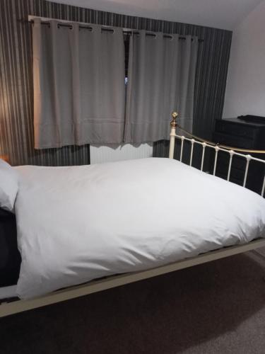 a bed with white sheets in front of a window at Southsea in Coedpoeth