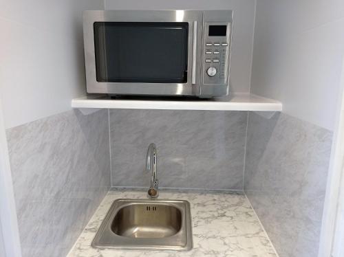 a microwave sitting on a shelf next to a sink at Mill View Apartment - Self contained one bed apartment in Oxford