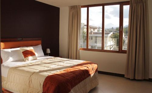 ein Schlafzimmer mit einem Bett und einem großen Fenster in der Unterkunft Hotel Casa Sakiwa in Machachi