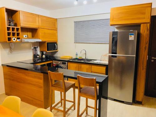 une cuisine avec un réfrigérateur en acier inoxydable et des armoires en bois dans l'établissement Beach Place Deluxe Apartment Cumbuco Sea View, à Cumbuco