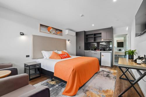 Golden Hotel في كرايستشيرش: غرفة نوم مع سرير وبطانية برتقالية