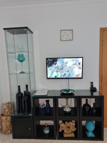 um armário preto com prateleiras de vidro e vasos sobre ele em Maligueira Apartment em Leiria