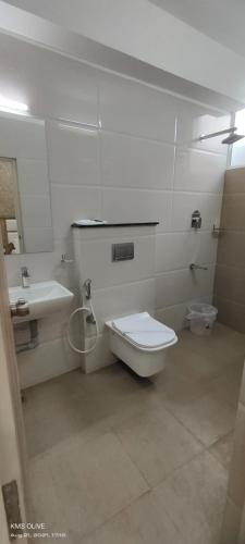 a white bathroom with a toilet and a sink at century courtyard in Chennai