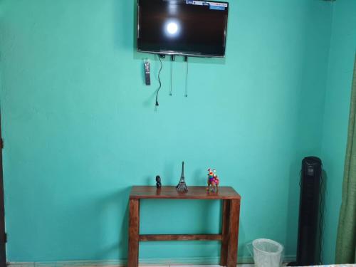 - une télévision sur un mur bleu avec une table en bois dans l'établissement HopeCR, à Alajuela