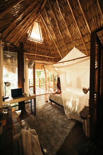 a person laying in a bed in a hut at BOA BOA Bacalar in Bacalar