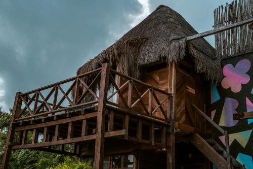a house with a thatched roof with a mural on it at BOA BOA Bacalar in Bacalar