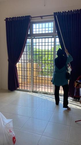 Homestay Chik Da في Kampong Alor Senjaya: امرأة تقف أمام نافذة تطل على الخارج