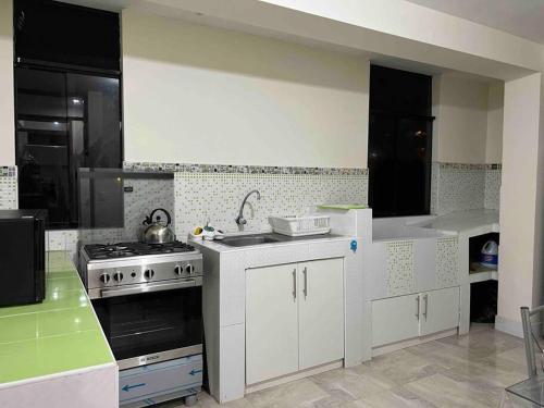a kitchen with white cabinets and a stove top oven at Apartamento exclusivo en Cusco cerca al aeropuerto in Cusco