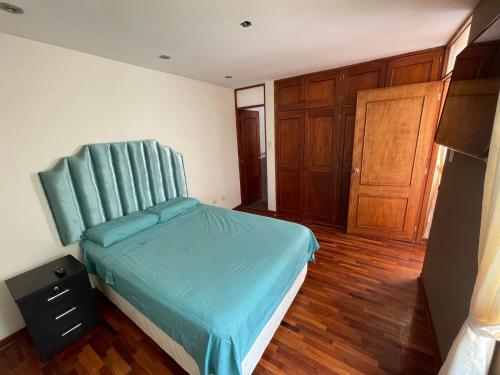 a bedroom with a bed with a blue headboard at Exclusivo Apartamento en el corazón de Trujillo in Trujillo
