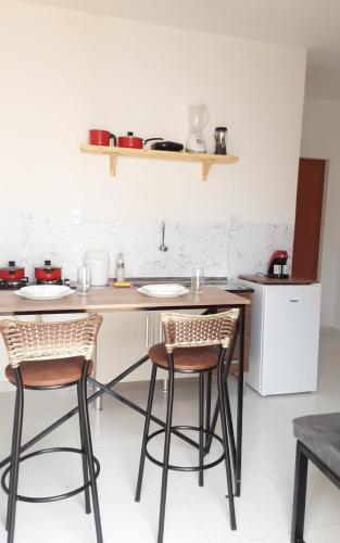 a kitchen with two stools and a table and a counter at Chales do delta Piauí in Parnaíba