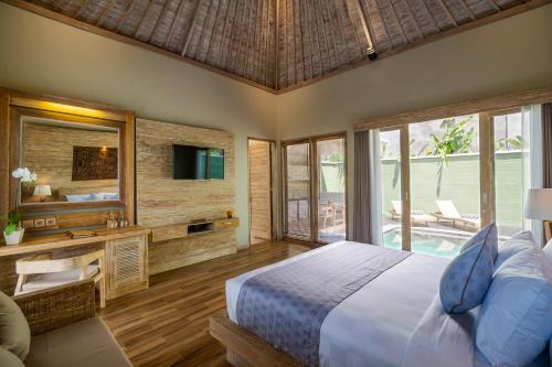 a bedroom with a bed and a tv and a mirror at Arkamara Dijiwa Ubud in Ubud