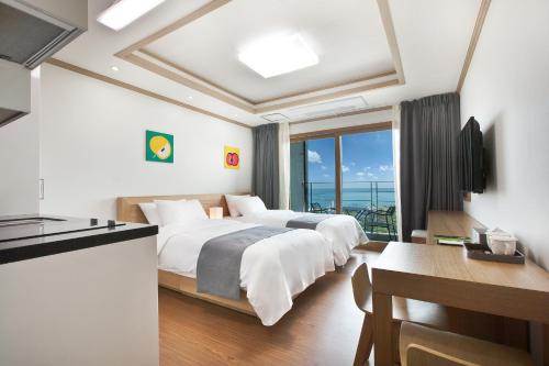 a hotel room with two beds and a balcony at Familia Hotel in Seogwipo