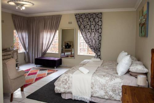 a bedroom with a bed and a chair and windows at Ailani Grey in Benoni