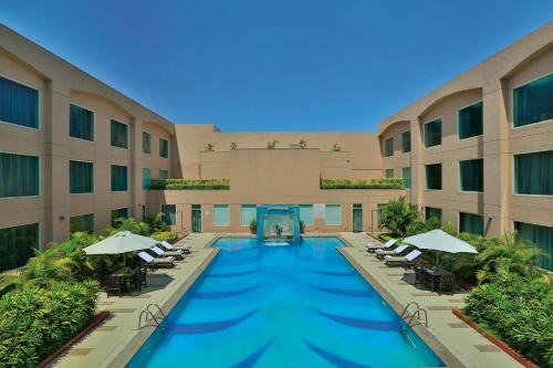 a swimming pool in a hotel with chairs and umbrellas at Yashail Hotel Haridwar in Haridwār