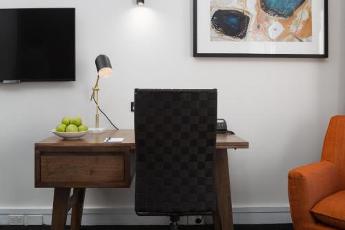 a chair sitting next to a desk with a bowl of apples at Esplanade Hotel Fremantle - by Rydges in Fremantle