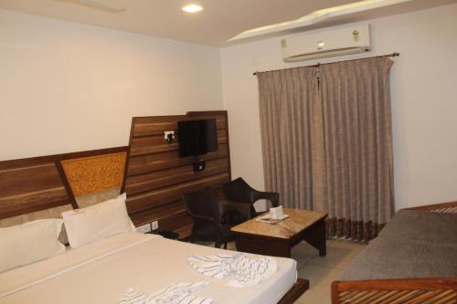 a hotel room with a bed and a desk and a television at Annai in Saravana Bhavan Fine stay and Restaurant in Velānganni