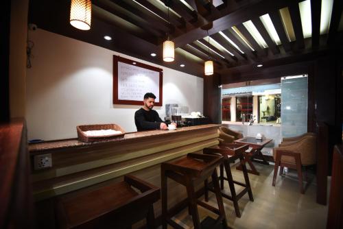 Un hombre de pie detrás de una barra en un restaurante. en Karma Hotel Nepal, en Katmandú