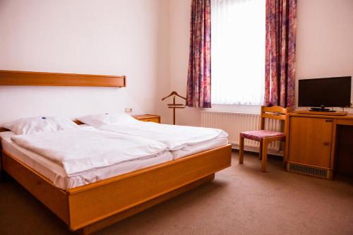 een slaapkamer met een bed, een tv en een stoel bij Hotel am Bahnhof in Stendal