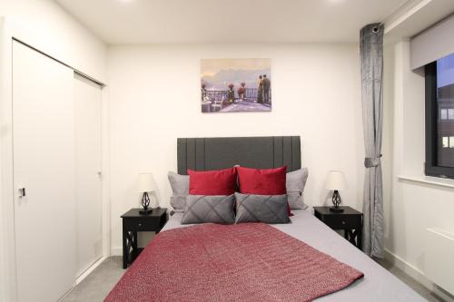 a bedroom with a large bed with red pillows at Virexxa Bedford Centre - Premier Suite - 2Bed Flat with Free Parking & Gym in Bedford