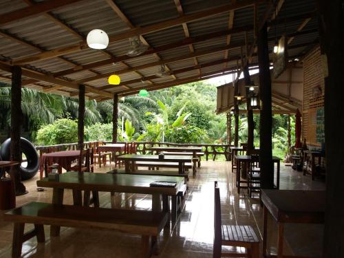 an empty restaurant with wooden tables and chairs at Khao Sok Palmview Resort in Khao Sok