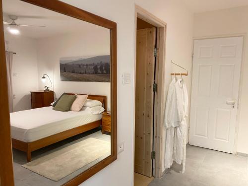a mirror in a bedroom with a bed and a bedroom door at תל שיבן אירוח בשעל in Sha'al