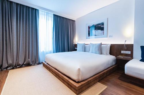 a bedroom with a large white bed and a window at QUU HOTEL Chiang Mai in Chiang Mai