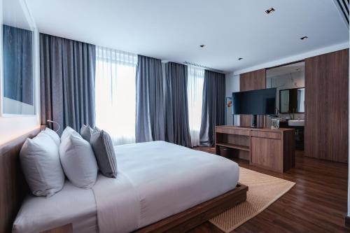 a hotel room with a bed and a television at QUU HOTEL Chiang Mai in Chiang Mai