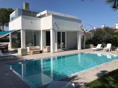 a villa with a swimming pool in front of a house at Super Villa With Private Pool in Isola Albarella in Isola Albarella