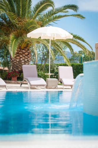 a swimming pool with two chairs and an umbrella at Hotel Ristorante Il Vascello in Costa Rei