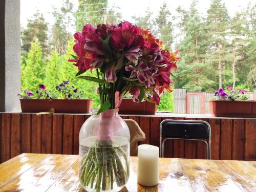 a vase filled with flowers on a table with a candle at садиба доличі in Bovkun