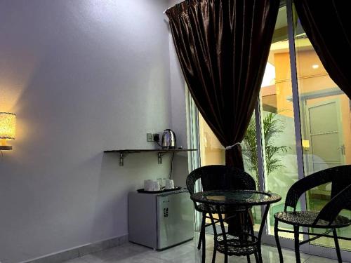 a room with a table and chairs and a window at Tokman Inn in Pantai Cenang