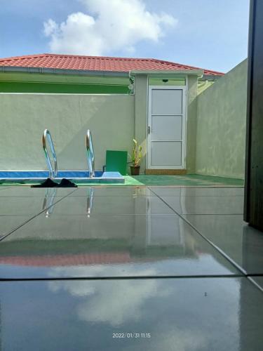 a glass table with two faucets in front of a pool at Tokman Inn in Pantai Cenang