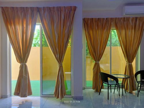 a room with curtains and a table and chairs at Tokman Inn in Pantai Cenang